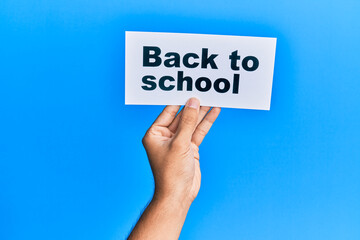 Hand of caucasian man holding paper with back to school message over isolated white background