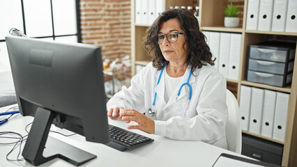 Middle age hispanic woman doctor using computer working at the clinic