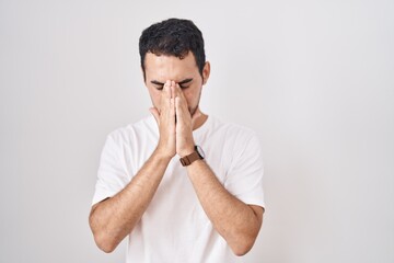 Handsome hispanic man standing over white background with sad expression covering face with hands while crying. depression concept.