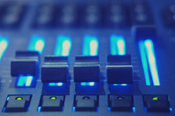 Sound mixer control panel with blue light. Shallow depth of field