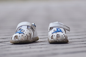 Pair of white sandals on the pavement. Selective focus.
