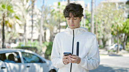 Young hispanic man using smartphone with serious expression at park