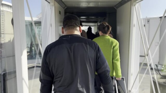Arriving by Day, Travelers Exiting Plane on Airport Jet Bridge during Daytime