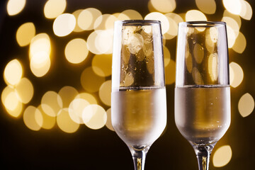 Two New Year's glasses of champagne with highlights on a colored background