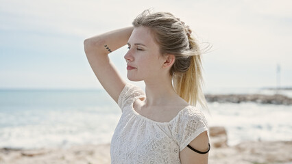 Fototapeta na wymiar Young blonde woman tourist touching hair at beach