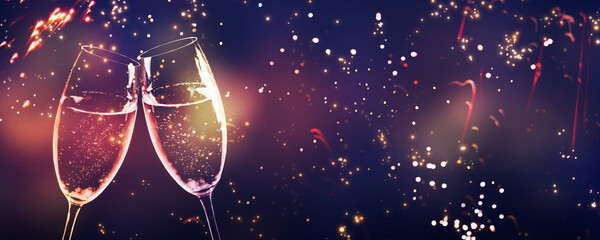 cheers with two toasting champagne flutes on glittering fireworks night sky with blurred lights and...