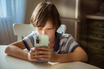 Cute child using smart phone, playing games. Children's screen addiction and parent control...