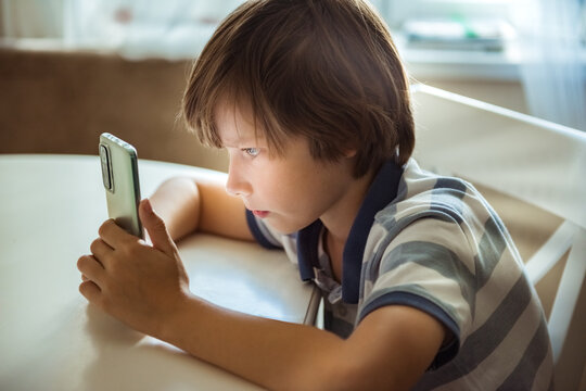 Cute child boy having fun using smartphone, enjoy amusing cool mobile application, play new video game, watch funny online video vlog. Modern tech, gen Z gadget overuse concept