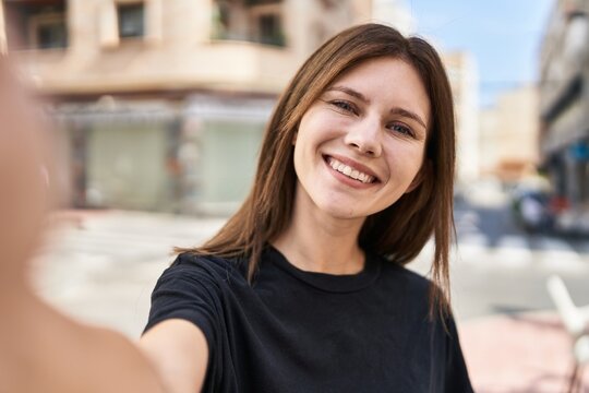 Young blonde woman smiling confident making selfie by the camera at street