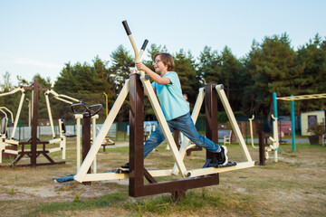 Fototapeta premium Healthy summer holidays. An active child boy is doing exercises on the sports ground in the park. Sport and active rest for children