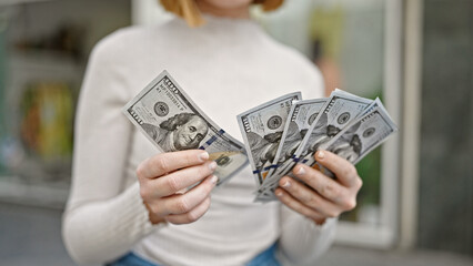 Young blonde woman counting dollars at street