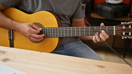 Obraz premium Young latin man musician playing classical guitar at music studio