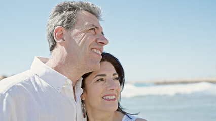 Senior man and woman couple smiling confident standing together at seaside