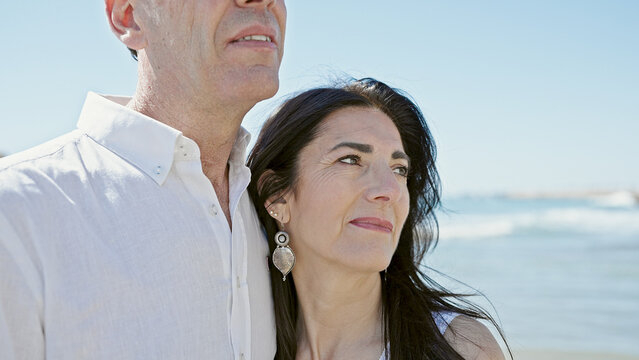 Senior man and woman couple standing together with relaxed expression at seaside