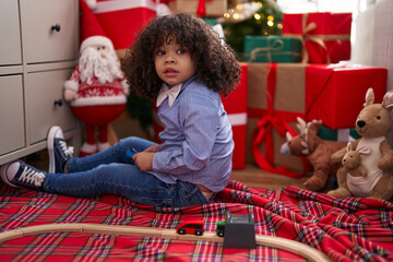 African american toddler playing with car toy sitting on floor by christmas tree at home