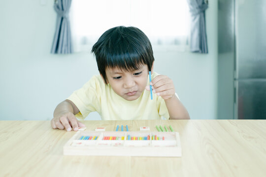 Asian kindergarten kid calculate and solve math problem. Little smart boy learning mathematics.