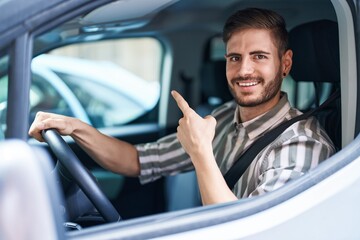 Hispanic man with beard driving car smiling happy pointing with hand and finger to the side