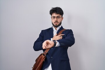 Hispanic man with beard wearing business clothes looking at the watch time worried, afraid of...
