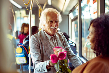 Senior man giving flowers to his significant other on the bus