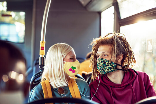 Diverse young couple sharing headphones together while riding the bus - Powered by Adobe