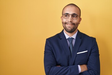 Hispanic man with beard wearing suit and tie smiling looking to the side and staring away thinking.