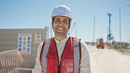 Young hispanic man builder smiling confident standing at street