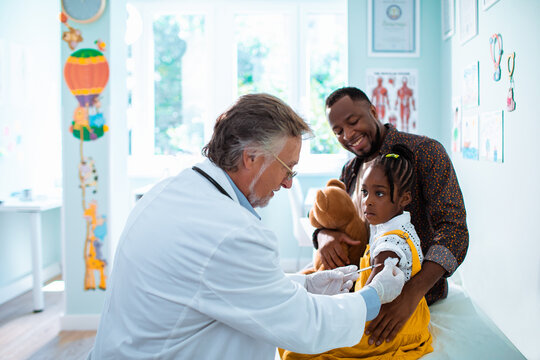 Senior pediatrician vaccinating a young girl patient at the clinic