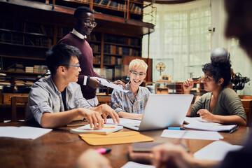 Young and diverse group of students working on a assignment together in the university library