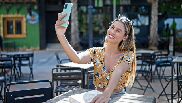 Young blonde woman tourist smiling confident make selfie by smartphone at coffee shop terrace