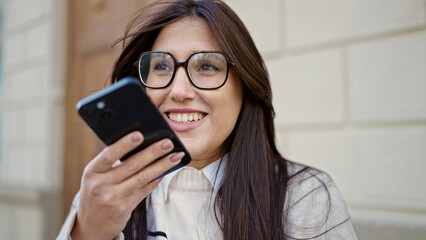 Young beautiful hispanic woman sending voice message with smartphone at street
