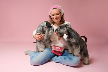 Woman holding a white miniature schnauzer dog, surrounded by happiness in the pink studio