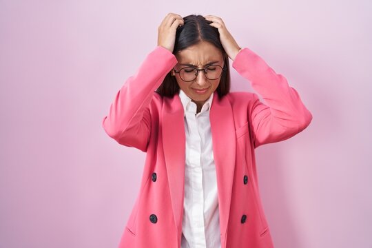 Young hispanic woman wearing business clothes and glasses suffering from headache desperate and stressed because pain and migraine. hands on head.