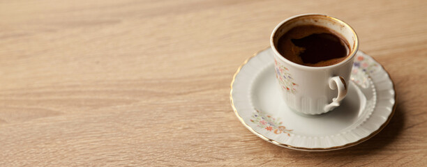 Traditional turkish coffee in patterned white cup on oak coffee table