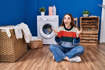 Young hispanic girl doing laundry celebrating victory with happy smile and winner expression with raised hands