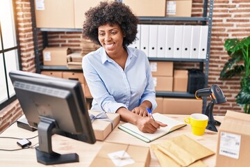 African american woman ecommerce business worker writing on notebook at office