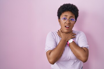 Young african american woman standing over pink background shouting and suffocate because painful strangle. health problem. asphyxiate and suicide concept.