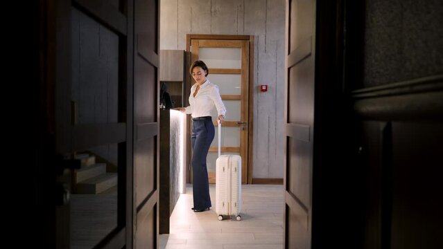 Business woman walking with luggage at the hotel into reception hall