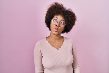 Young african american woman standing over pink background making fish face with lips, crazy and comical gesture. funny expression.