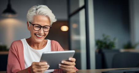 A smiling older woman embracing technology, showing how enthusiastically she uses a tablet, copy space - obrazy, fototapety, plakaty