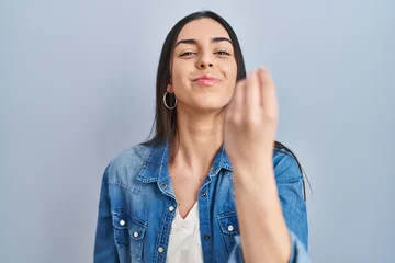 Fotobehang Hispanic woman standing over blue background doing italian gesture with hand and fingers confident expression © Krakenimages.com