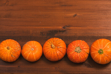 autumn orange halloween pumpkins over rustic wooden background. Сoncept Halloween celebration background, fall harvest, minimalism holiday decoration template. Top view, flat lay, copy space