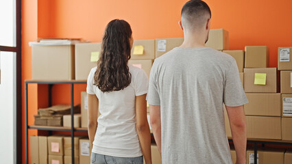 Backwards bond, two workers - a man and woman, standing together in the office, embodying teamwork in every parcel of their business