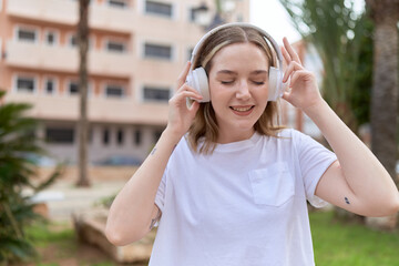 Young caucasian woman listening to music at park