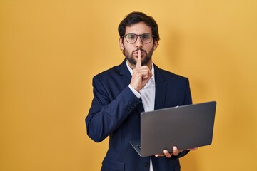 Handsome latin man working using computer laptop asking to be quiet with finger on lips. silence and secret concept.
