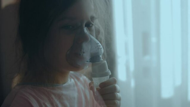 Little girl making inhalation with nebulizer at home. Inhalation nebulizer with medication steam for cough. State of weakness.