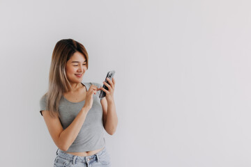 Asian Thai woman wear grey, happy smiling while using smartphone, texting and chatting with someone, isolated over white background.