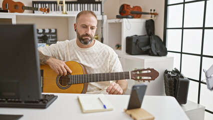 Young man recording video by smartphone playing classical guitar at music studio