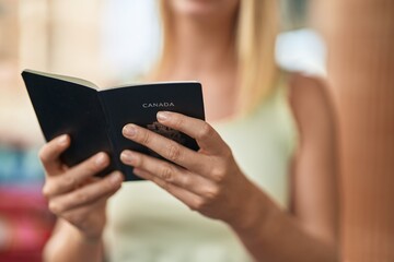 Young blonde woman reading canada passport at street