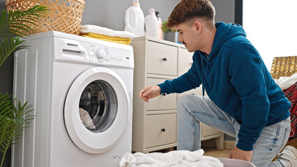 Young hispanic man washing clothes at laundry room
