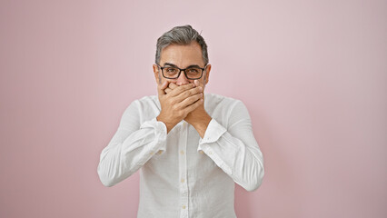 Wow! amazed young hispanic man with grey-haired expression, hands covering open mouth, standing over pink isolated background!